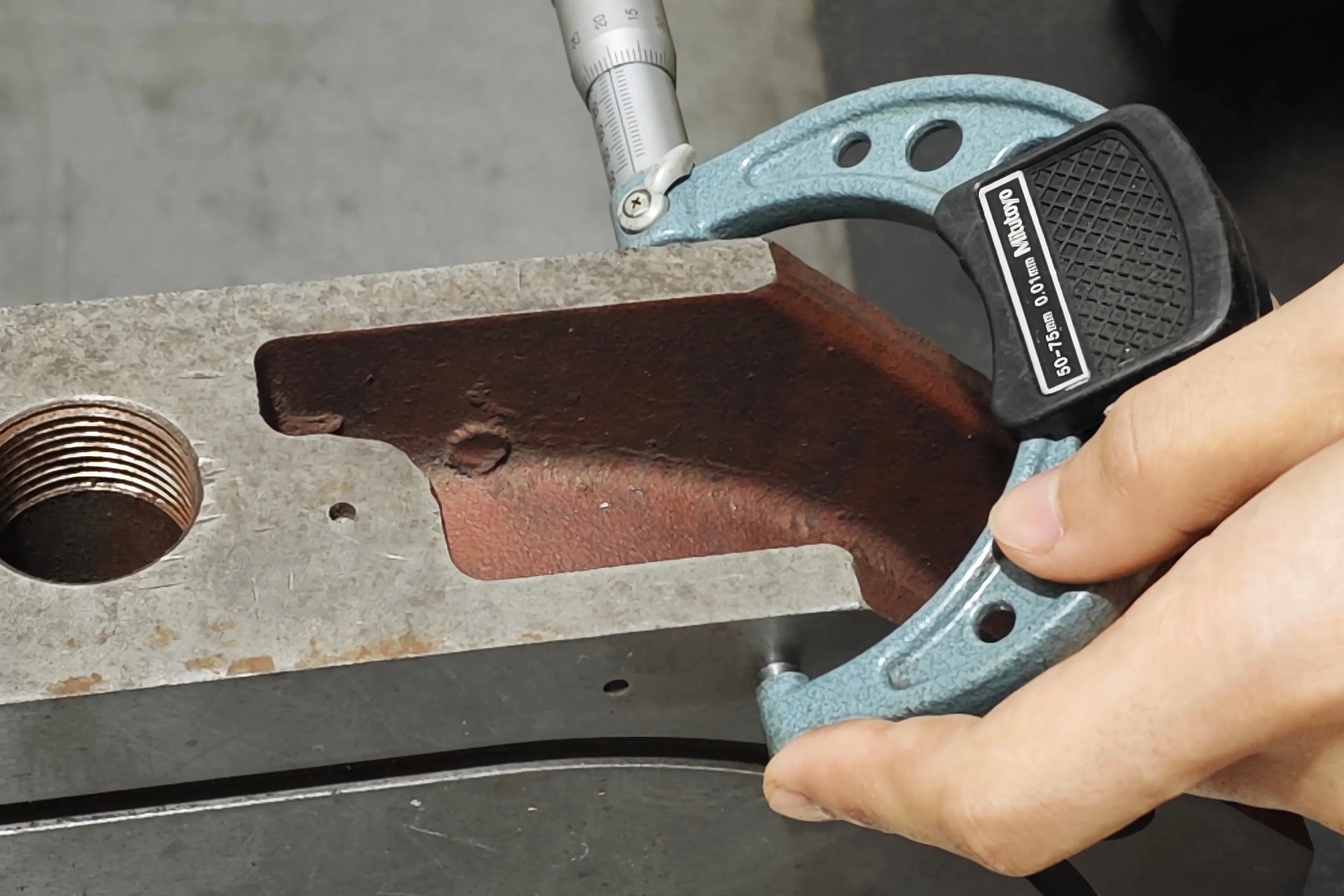 Micrometer verifying ground thickness on a precision-ground component after surface grinding at SCPM