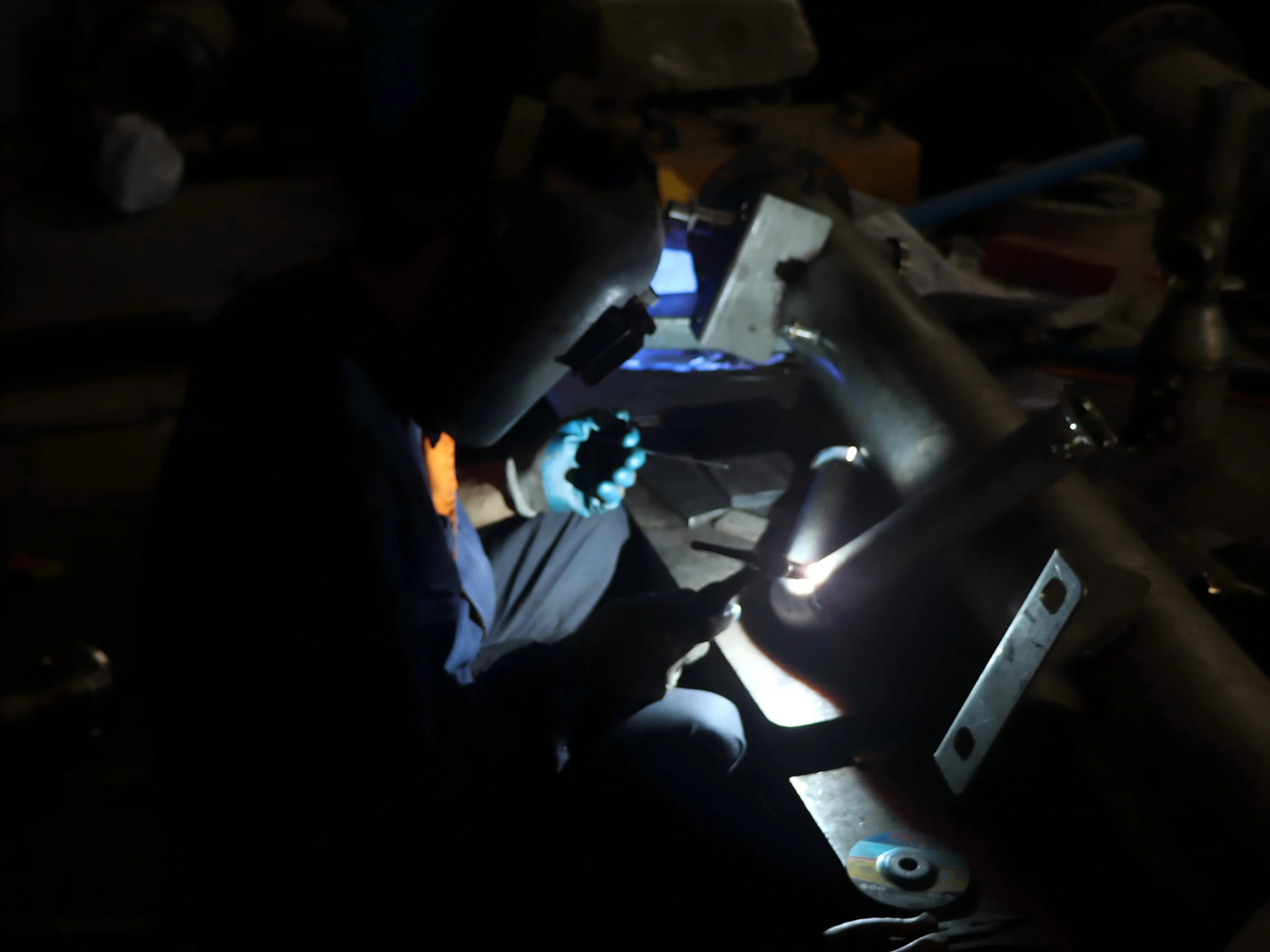 Welder running the joints — sub-parts held in the pre-weld fixture, welded in sequence to keep distortion in check