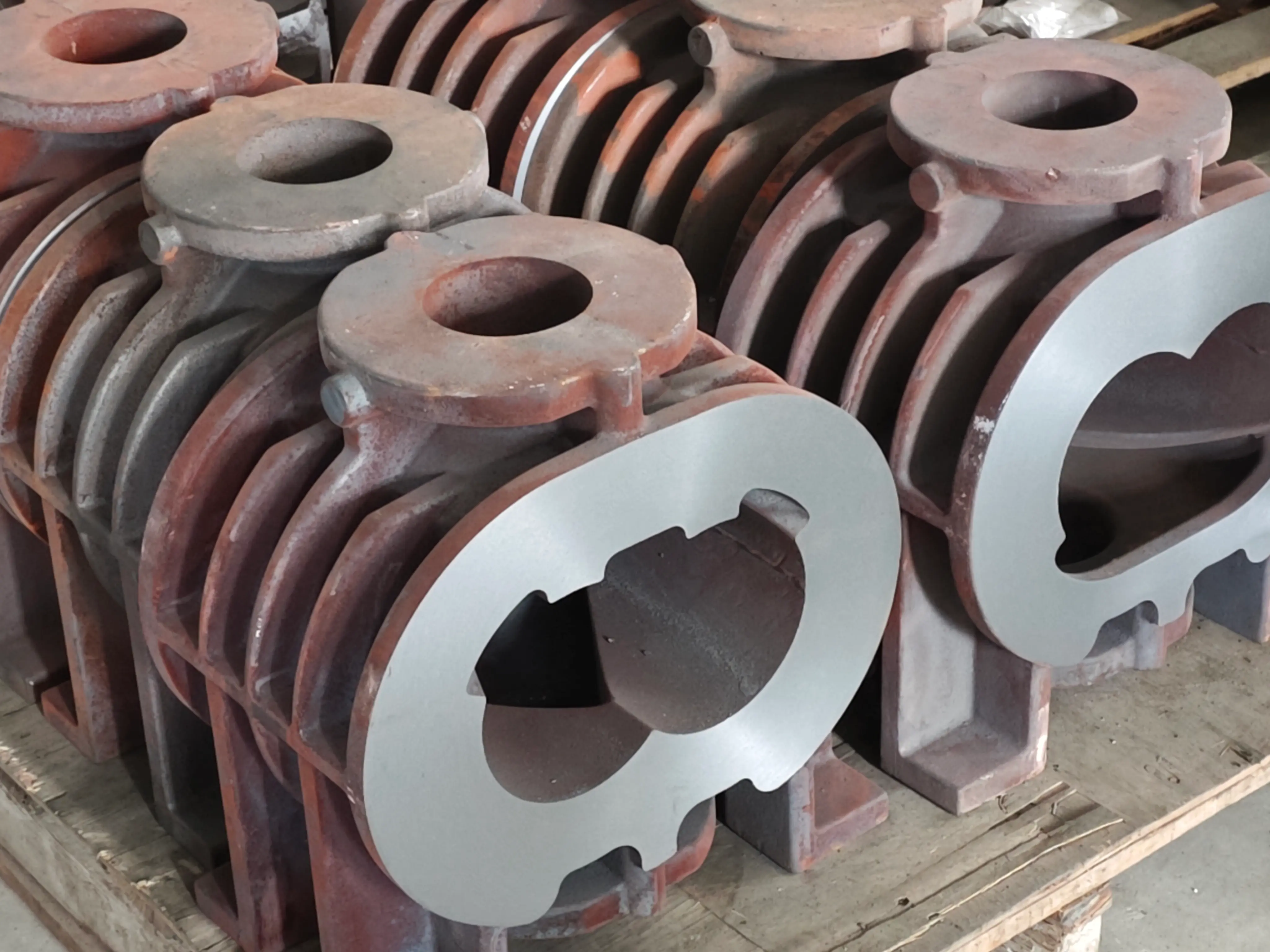 Lost-foam cast blank and welded fabricated blank for the same dry screw pump housing, placed side by side to show the difference in raw material profile and machining allowance
