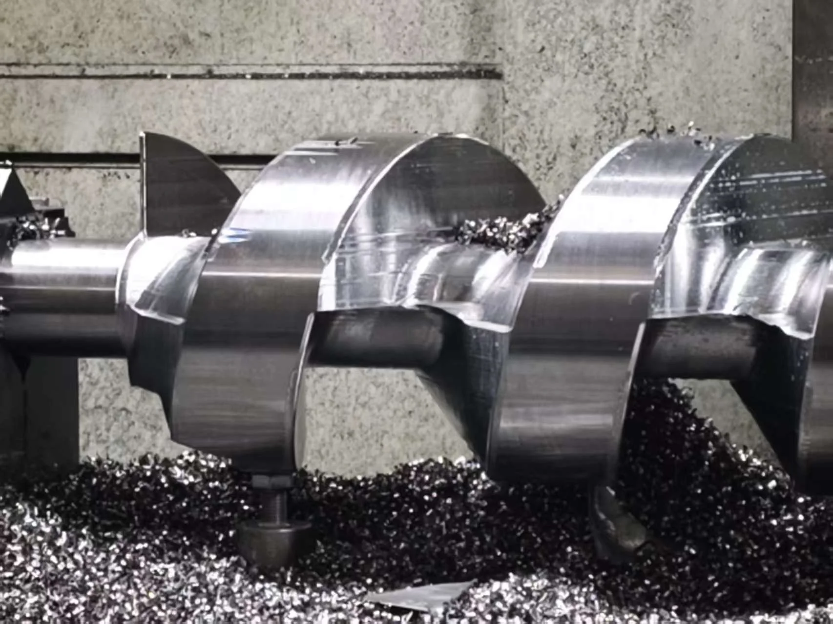Compressor rotor after 3-axis roughing on a standard machining center, with controlled stock left on the lobes for finishing and chips still piled around the workpiece